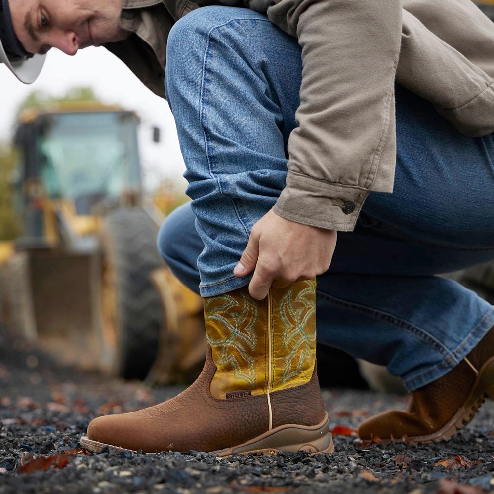 A man wearing the Roustabout 11" Steel Toe Waterproof Work Boot in brown kneeling at a work site.